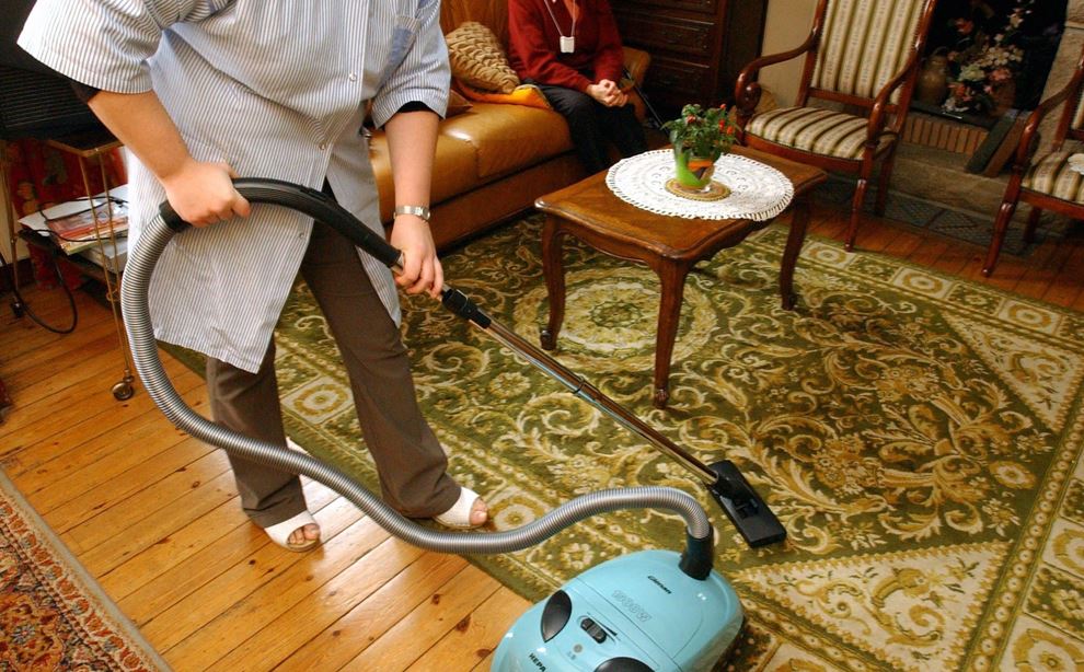 Hjemmehjælper støvsuger i ældre dames hjem.
