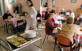 Ældre mennesker sidder sammen om et bord og spiser.