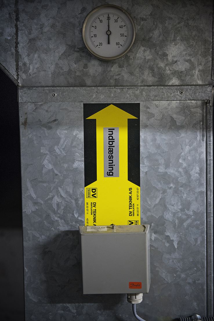 Et billede af et gult ventilationsanlæg der hænger på en væg