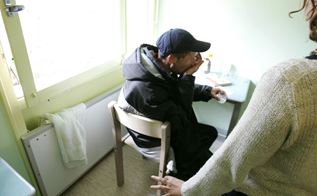 Psykiatrisk patient spiser medicin, mens en plejer kigger på.