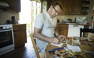 Kim Fleron sidder i sit køkken og bladrer i tilbudskataloger, mens han skriver madplan