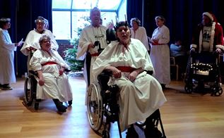 Beboere på plejecenter går Luciaoptog i hvide kjoler og med lys