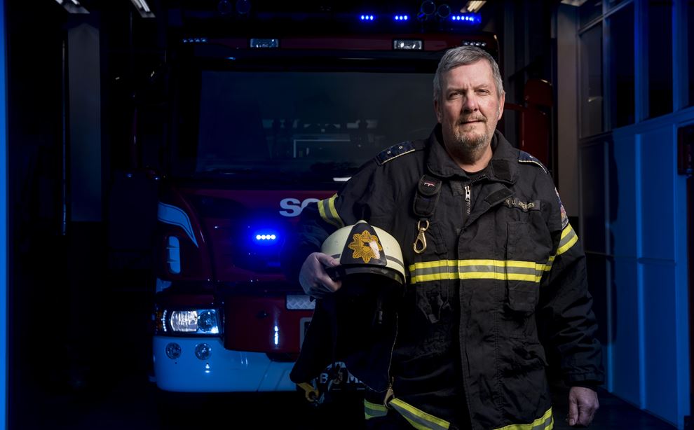 Brandmand Erik Uldall Andersen foran en brandbil