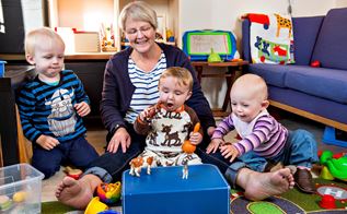 Dagplejer Lisbet Nørby Nielsen i Holstebo sidder på gulvet med tre dagplejebørn