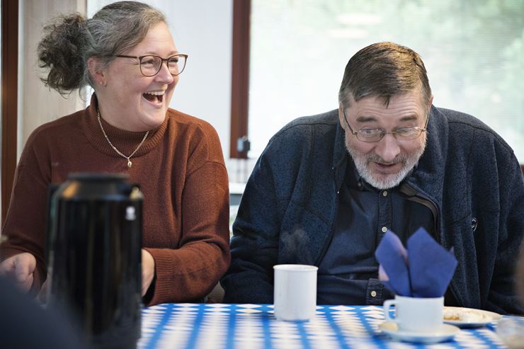 En mand og en kvinde sidder ved siden af hinanden ved et bord og griner