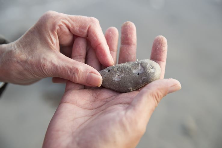 En hånd holder en sted frem, mens en andens hånd mærker på spidsen af stenen