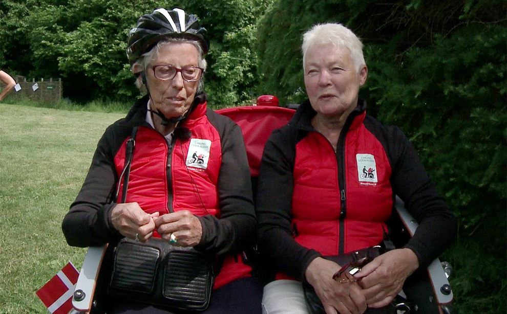 To ældre kvinder sidder ved siden af hinanden i cykelvogn