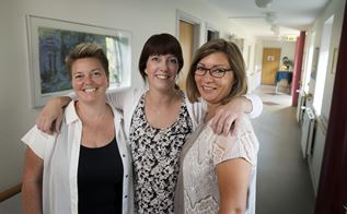 Tre kvindelige ansatte på Plejecentret Lollandshus i Aalborg står sammen på en gang.