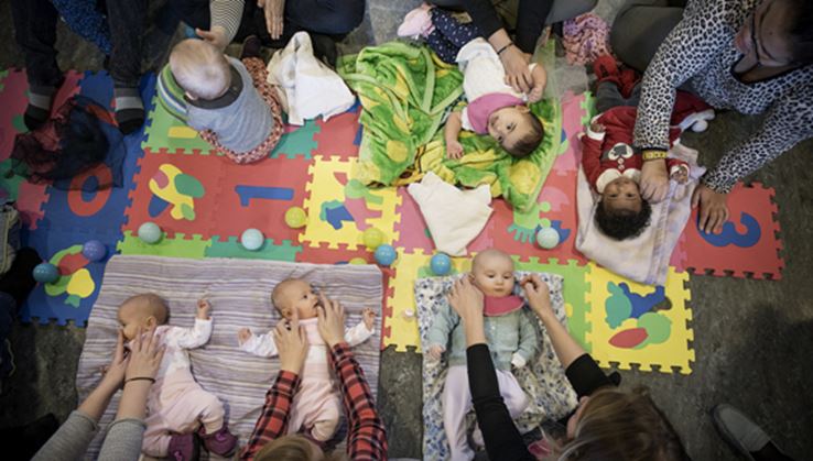 En gruppe babyer ligger et på underlag på gulvet.