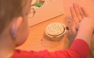 Et dagplejebarn er i gang med at pynte en cupcake med krymmel