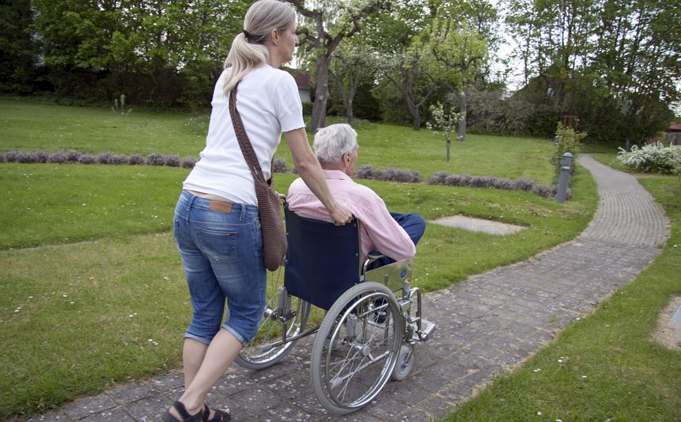 Kvinder skubber kørestol med en ældre dame.