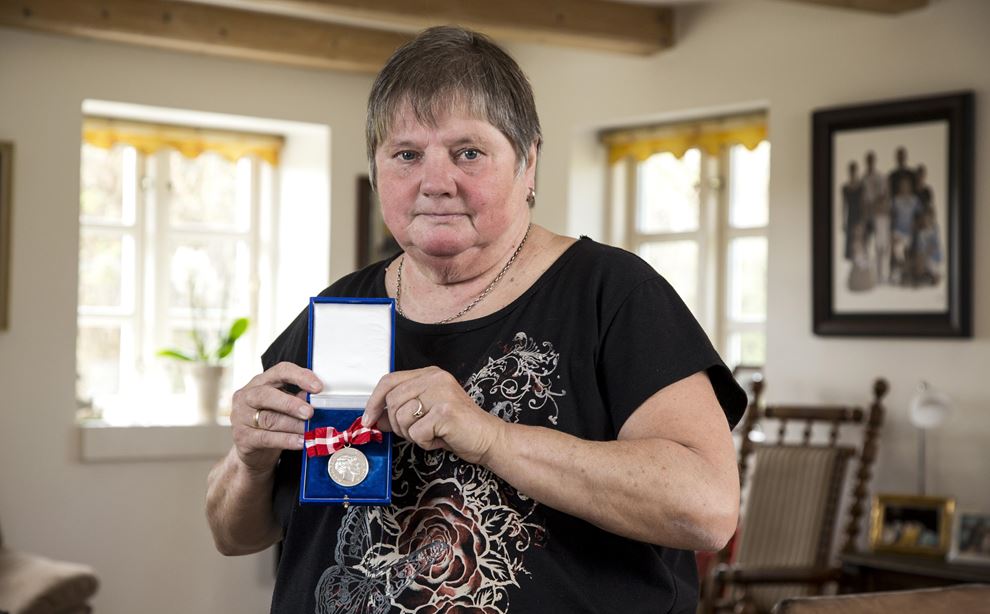 Kvinde står i stue og fremviser medalje