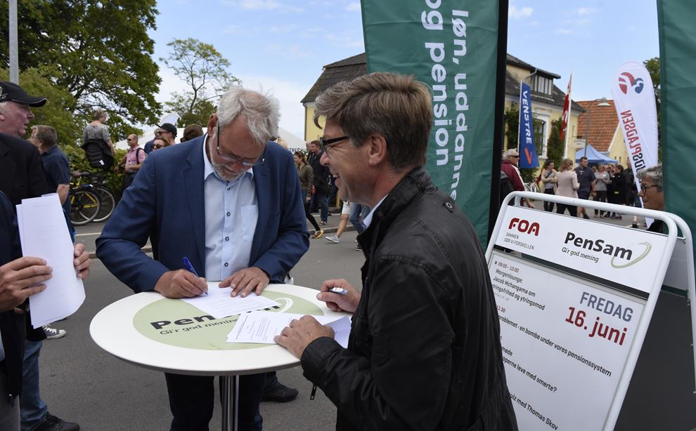 To mænd står og skriver under på en overenskomst under Folkemødet på Bornholm
