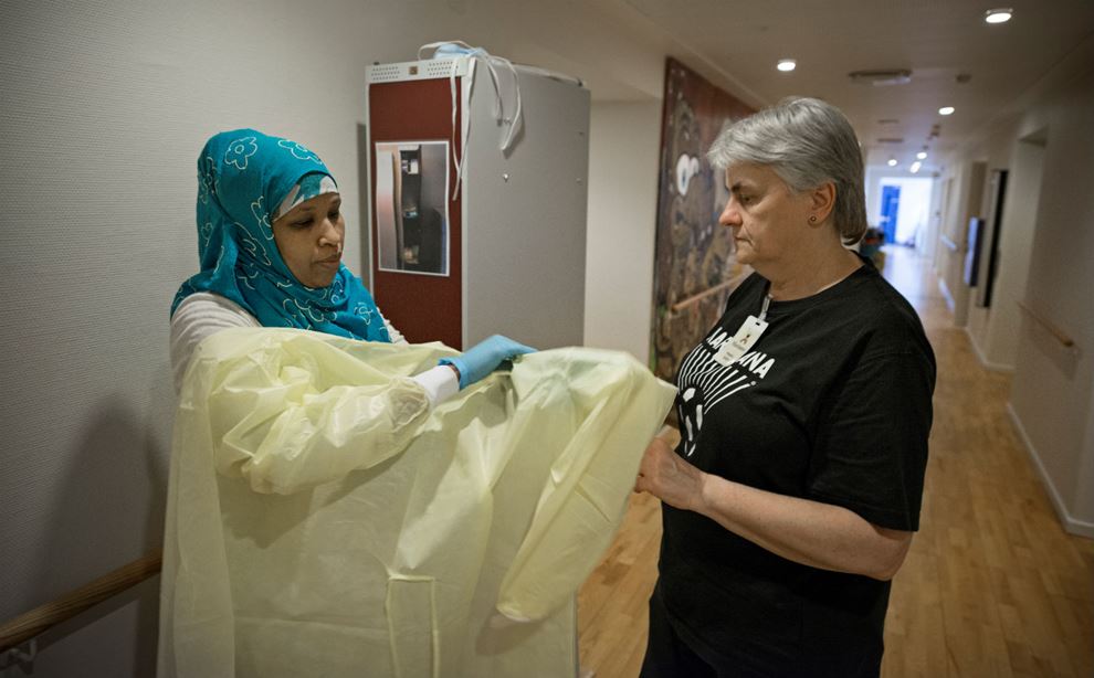 To rengøringsmedarbejdere hjælper hinanden i tøjet