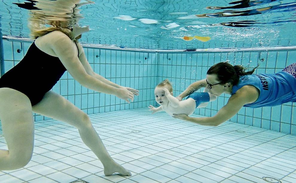  Instruktør laver dyk med baby til babysvømning og moderen tager imod