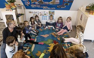 Børn og voksne sidder i rundkreds i en børnehave