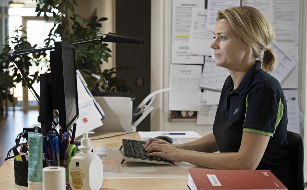 En social- og sundhedsassistent arbejder ved en computer