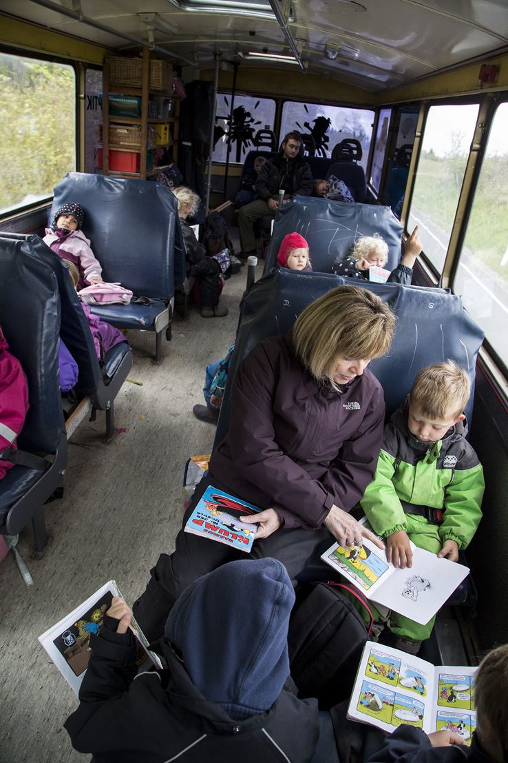 En kvinde sidder sammen en masse børn i en bus