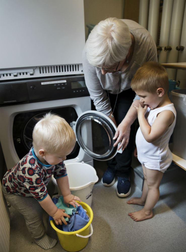 Børn og voksen hjælpes ad om vasketøjet i børnehaven