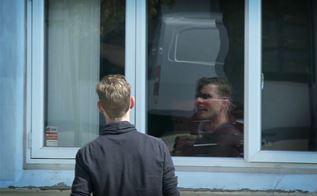 En mand taler med en person bag et vindue