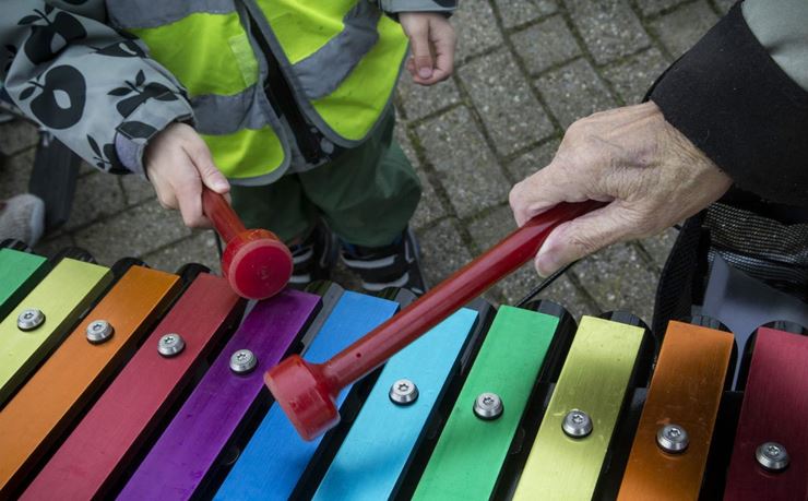 Beboer på plejehjem og børnehavebarn spiller xylofon