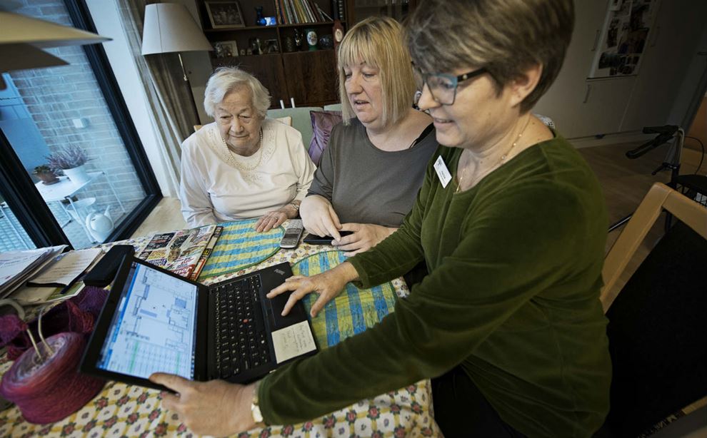 En ældre borger ser på en computerskærm sammen med to social- og sundhedshjælpere