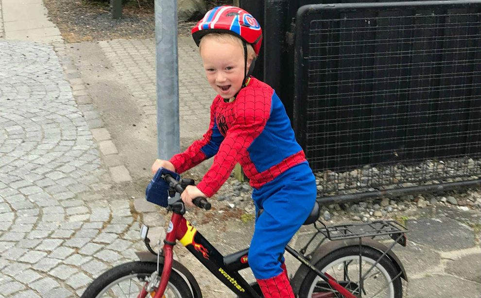 Dreng klædt ud som Spiderman, som kører på en cykel