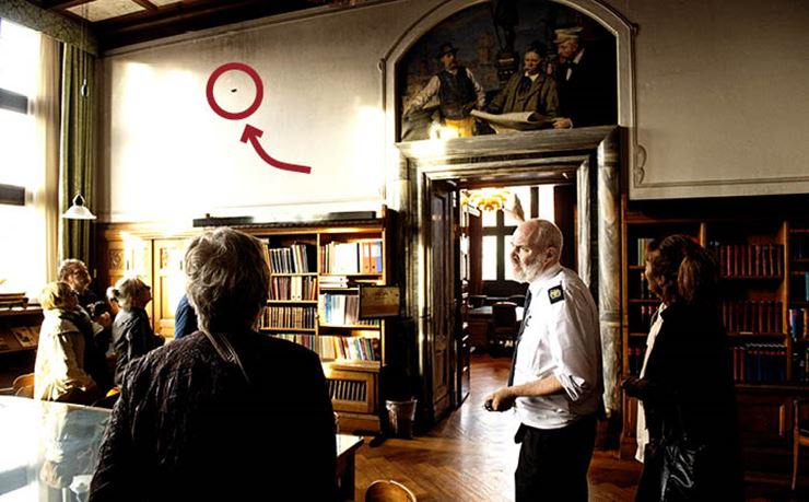 En rådhusbetjent viser et skudhul i væggen på Københavns Rådhus