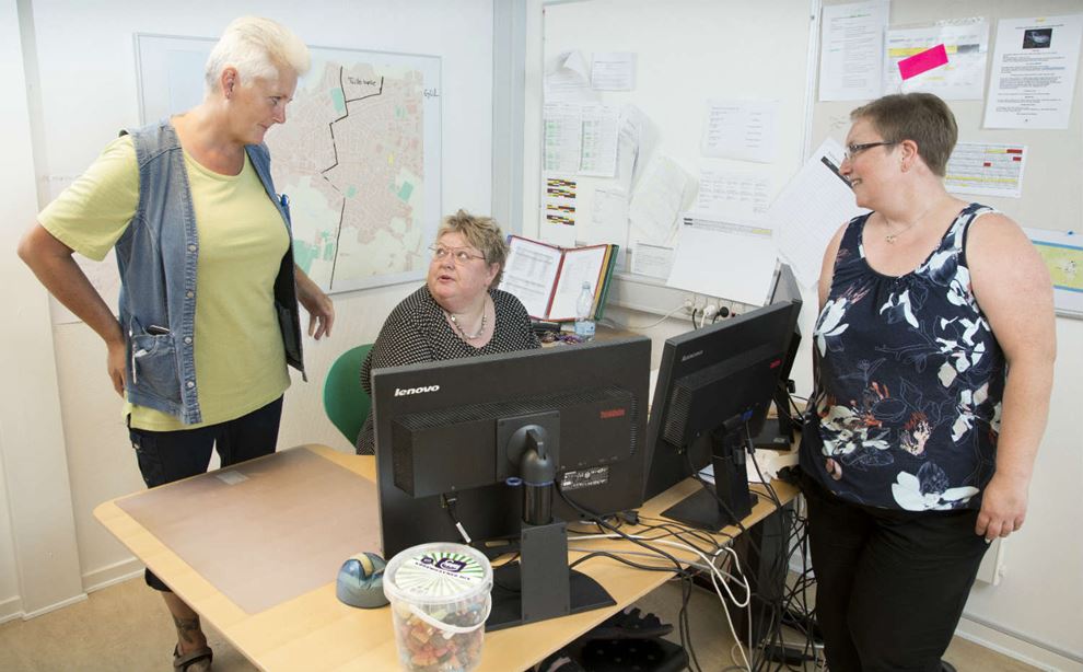 Tre kvinder ved en computer planlægger køretider i hjemmeplejen