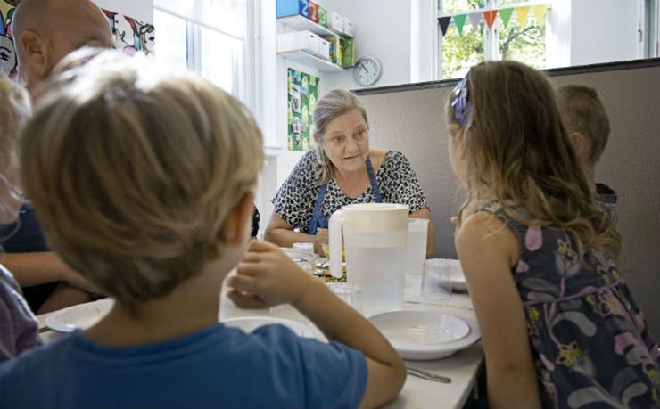 Køkkenmedhjælper snakker med børn om maden