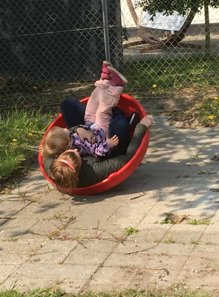To børn leger i en rød skal på jorden.