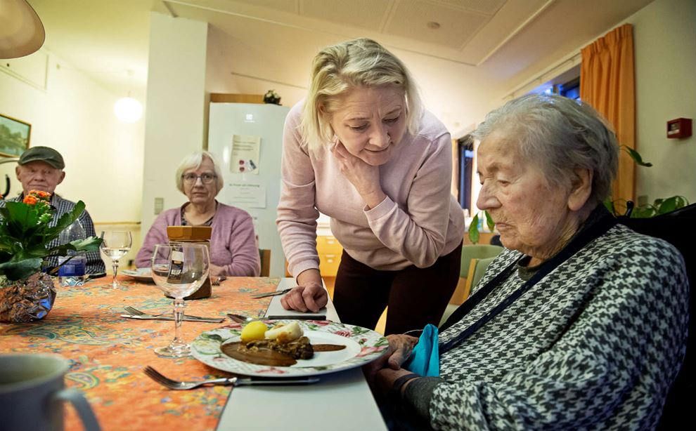 En medarbejder på et plejehjem hjælper de ældre med at spise