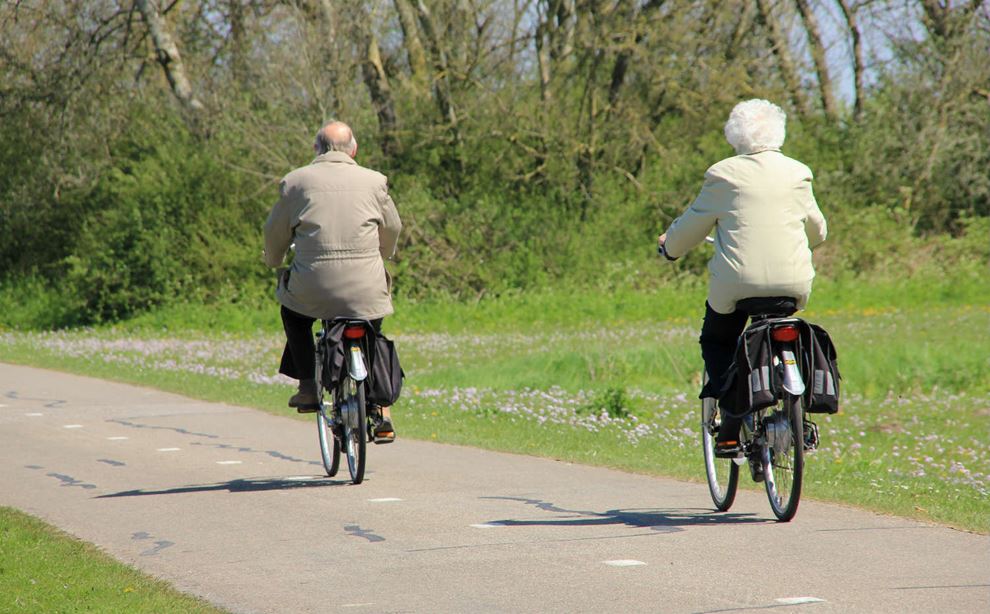 Ældre mand og kvinder køre på cykel i naturområde