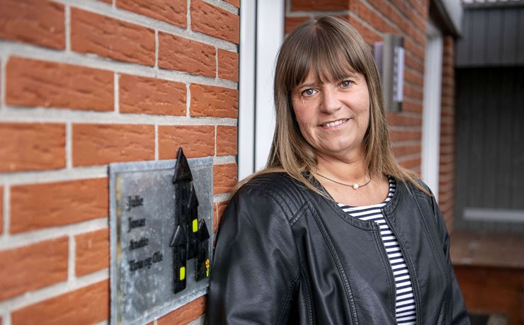 Tina Jensen, tidligere dagplejer, står op ad en rød mur ved sit hus.