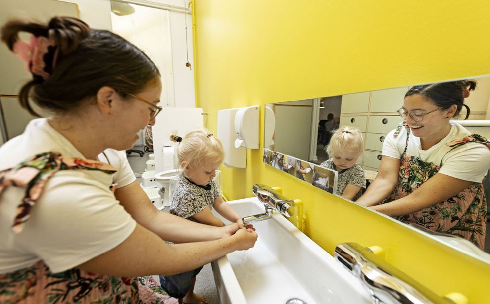 Voksen viser barn hvordan man vasker hænder