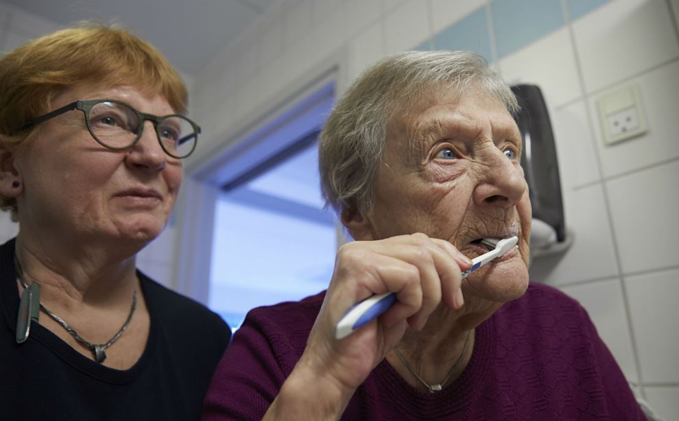 Lisbeth Andersen hjælper Inger Jensen med at børste tænder