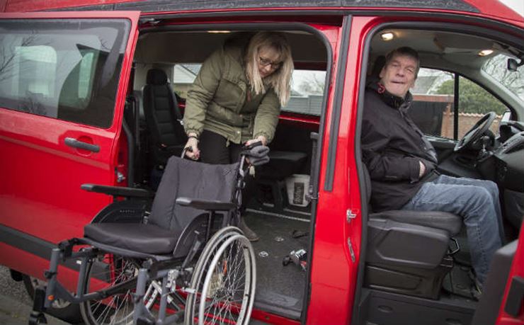 Susanne Snitgaard læsser en kørestol i handikapbussen