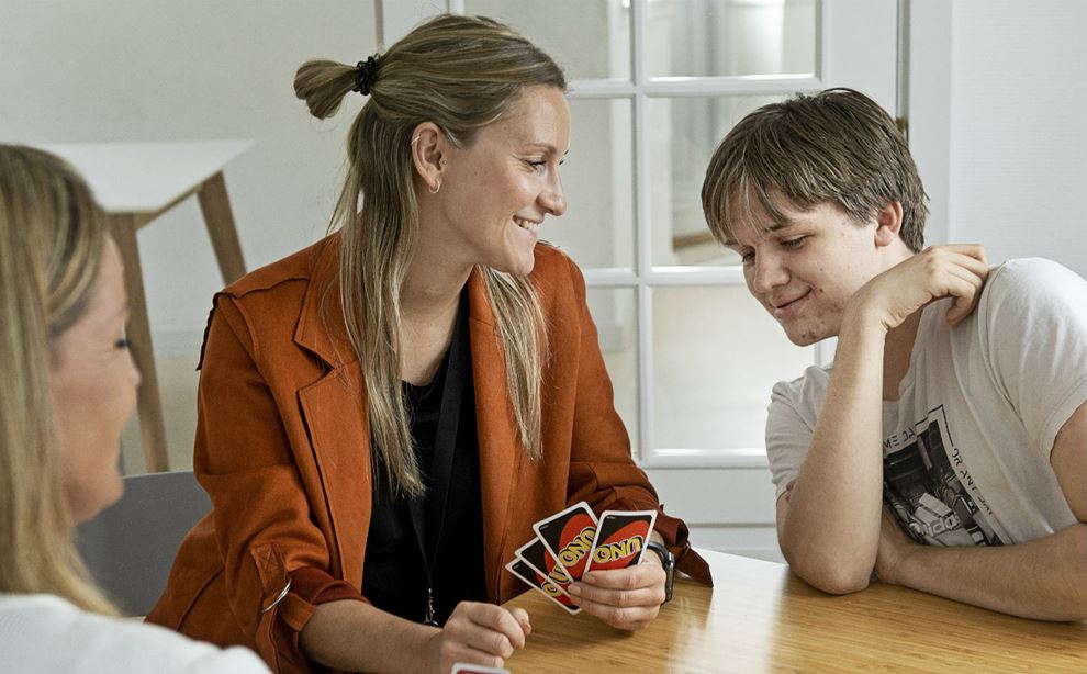 Pædagogmedhjælper Heidi Avnsø Petersen, pædagog Michelle Harboe og Andreas Bjørneboe tager et spil UNO.