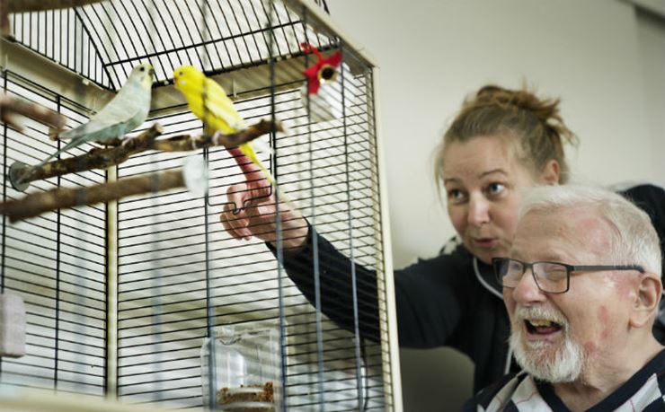plejehjemsbeboer kigger på fugl i bur