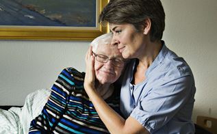 Social- og sundhedshjælper krammer ældre beboer for at forebygge hudsult