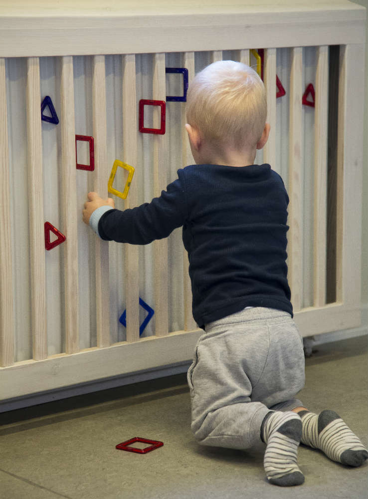 Lille dreng hænger magneter på radiator i dagplejen Odense syd