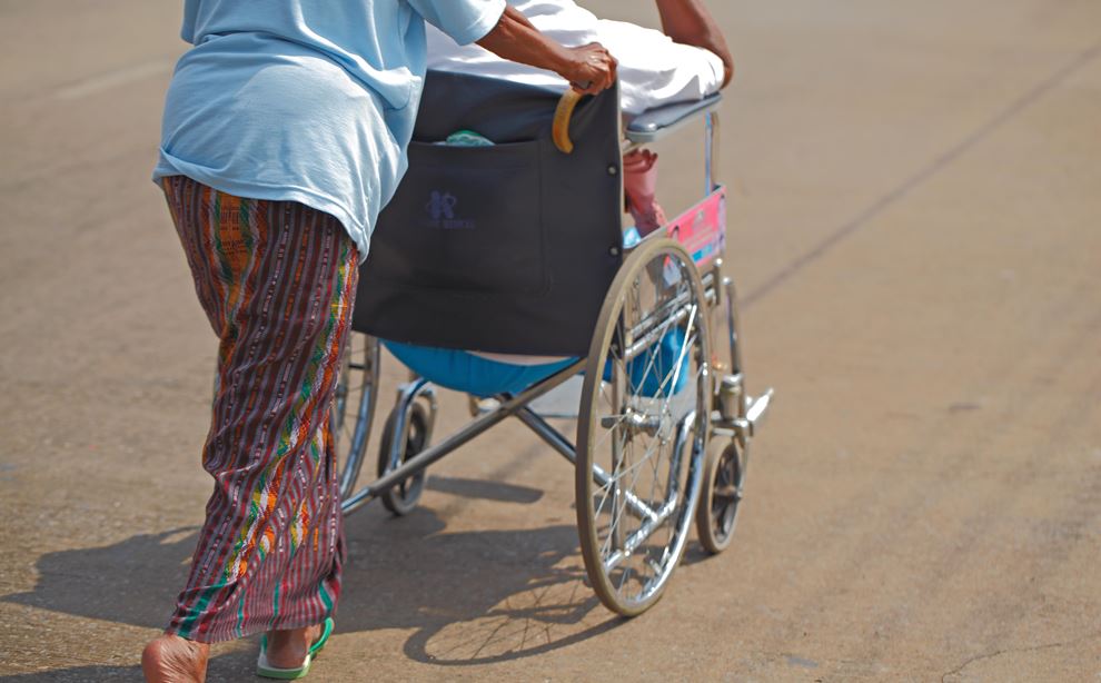 Kvinde skubber kørestol med handicappet foran sig