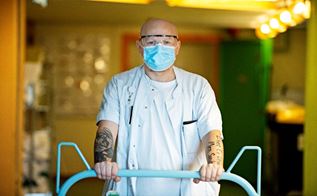 Michael Byfoged med mundbind og briller skubber en seng på Herlev Hospital