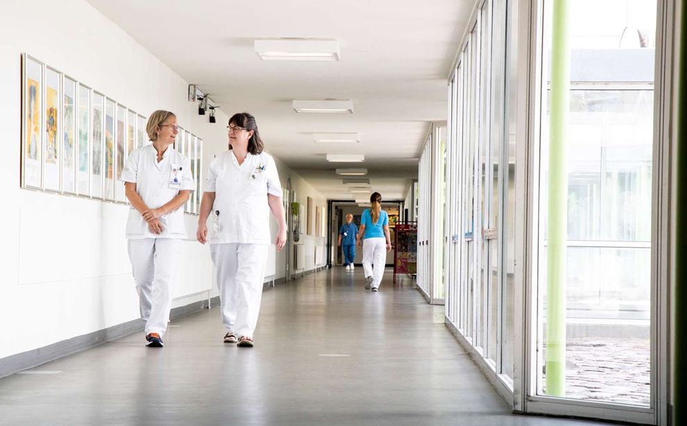 To sosu'er på arbejde på Odense Universitetshospital går på en lang hvid gang
