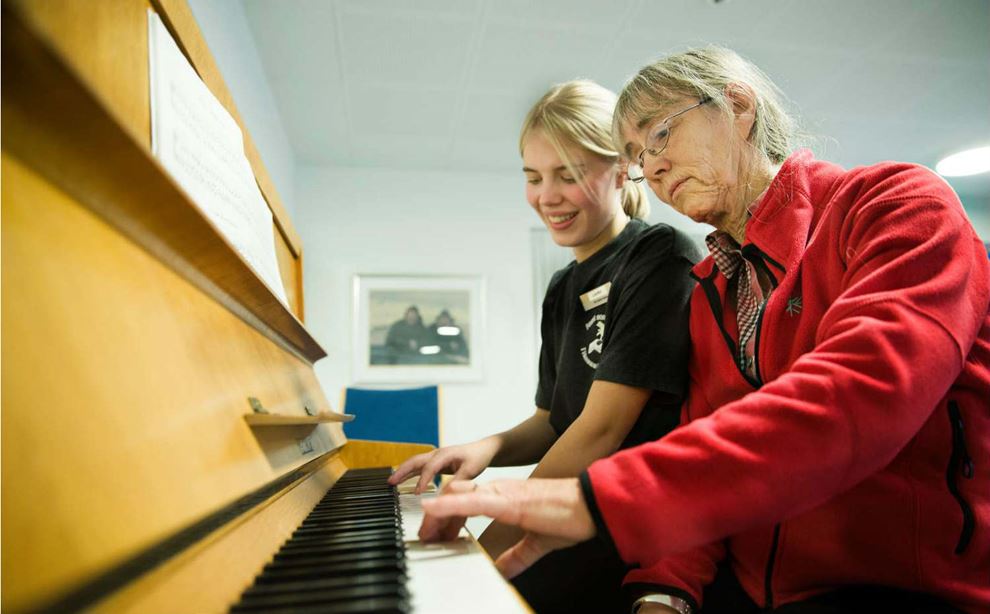 En yngre og en ældre kvinde spiller klaver sammen