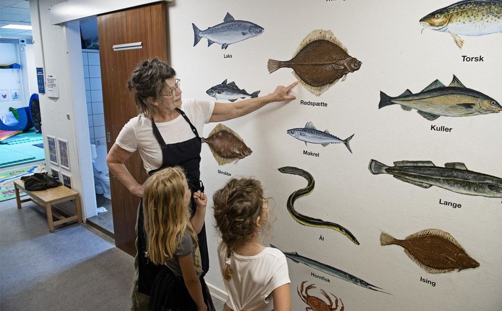 Køkkenansvarlig Susie Østergaard Lassen peger på billeder af fisk