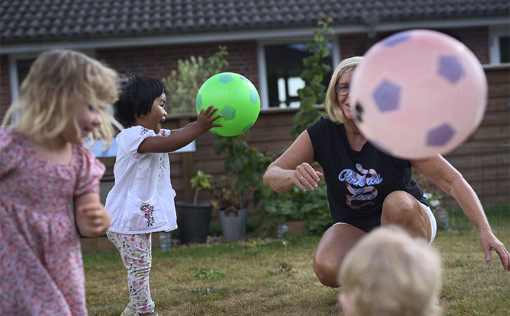 Lisbeth Ellebjerg spiller bold med tre børn på græsplæne foran hus