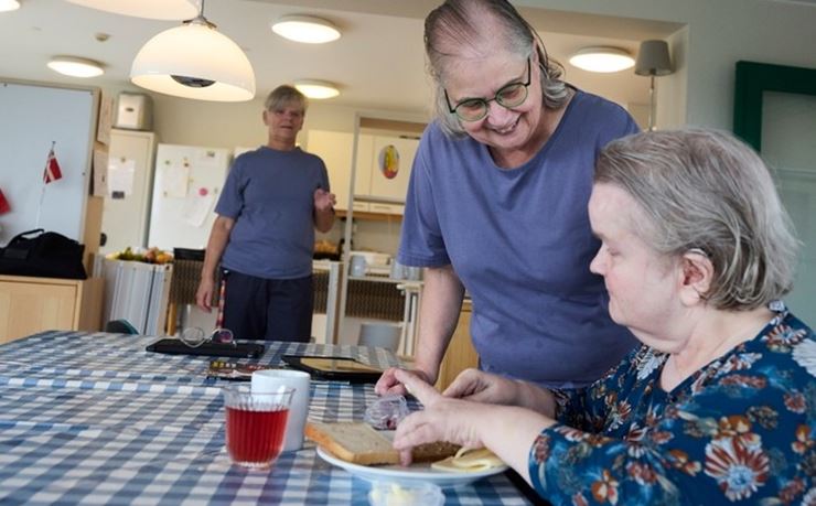 Social- og sundhedshjælper hjælper dame med at smøre sin frokost